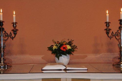 Altare med blommor, ljusstakar och en öppen bibel